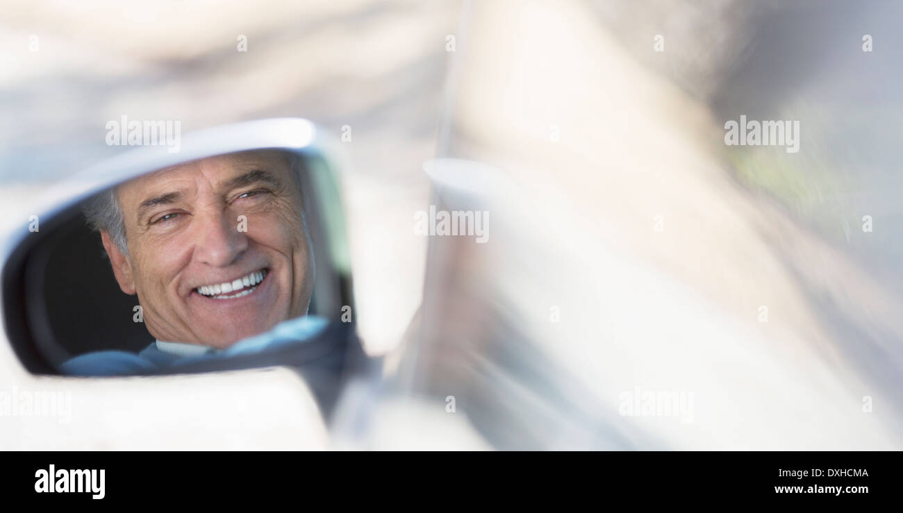 Reflejo de sonriente hombre senior en coche Espejo de vista lateral Foto de stock