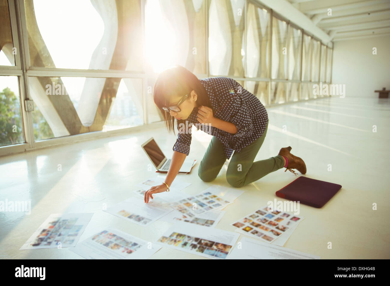 Revisar la empresaria creativa fotografía pruebas sobre el suelo de su oficina Foto de stock
