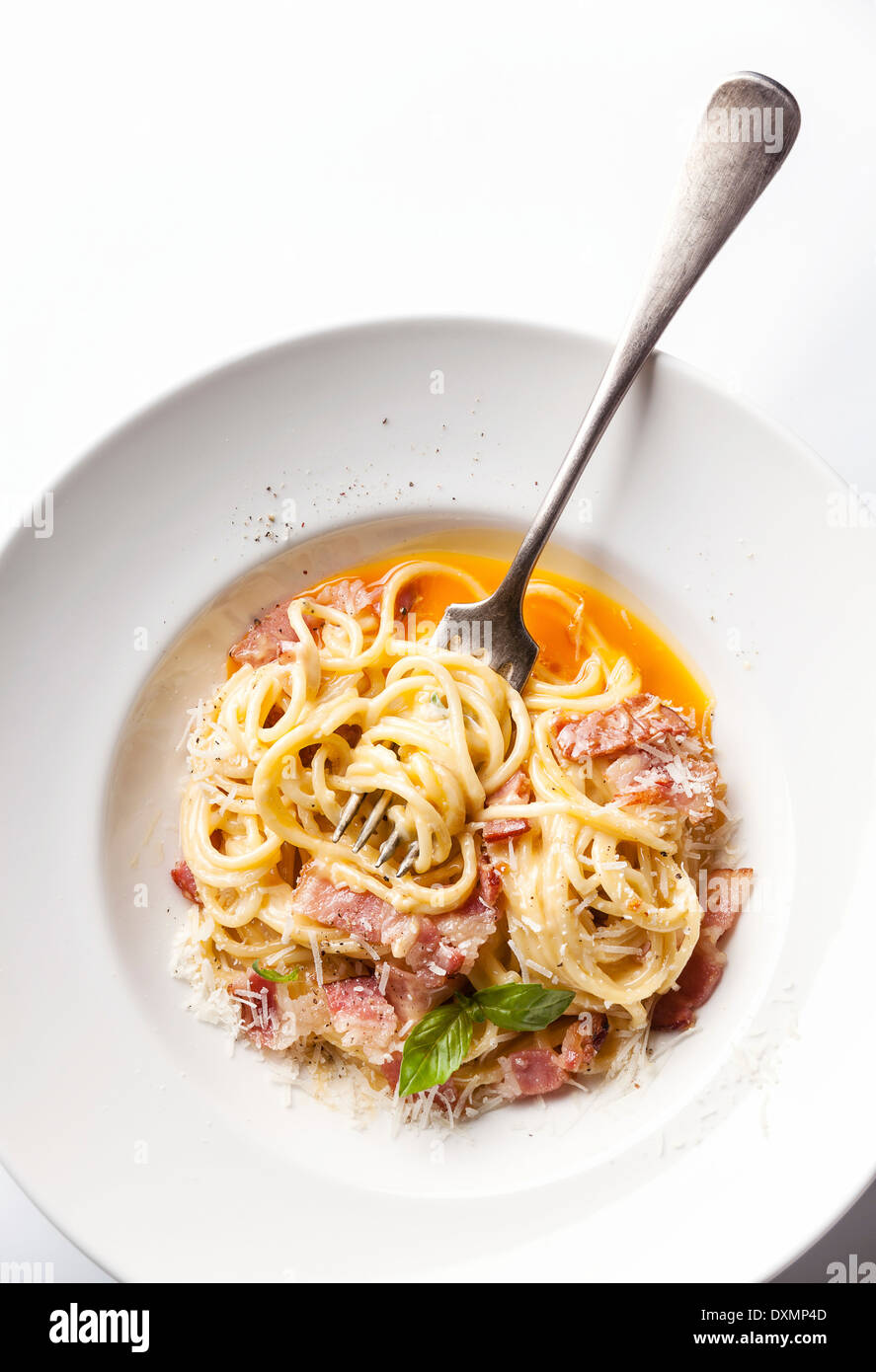 Pasta Carbonara sobre placa blanca con queso parmesano y yema de huevo