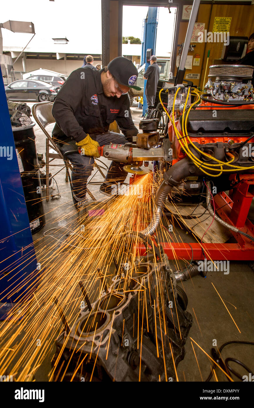 Las chispas vuelan como un adolescente muele un metal de montaje del motor en auto shop clase en San Clemente, CA. Foto de stock