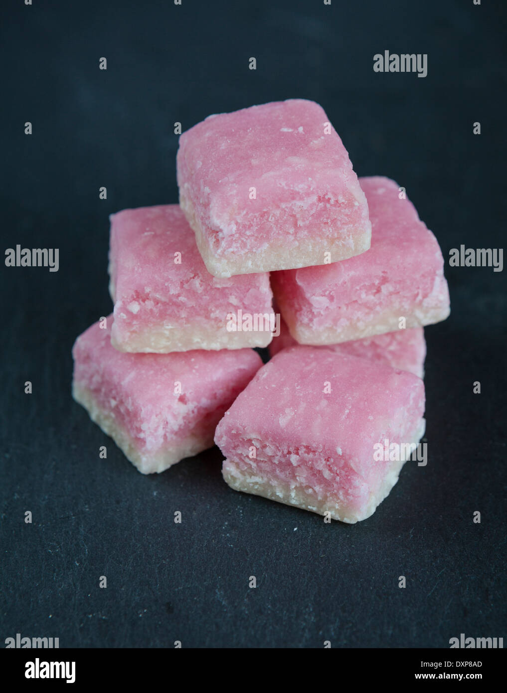 Un montón de rosa y blanco hielo de coco, un dulce tradicional hecha de coco desecado y azúcar, sobre un plato de servir de pizarra. Foto de stock