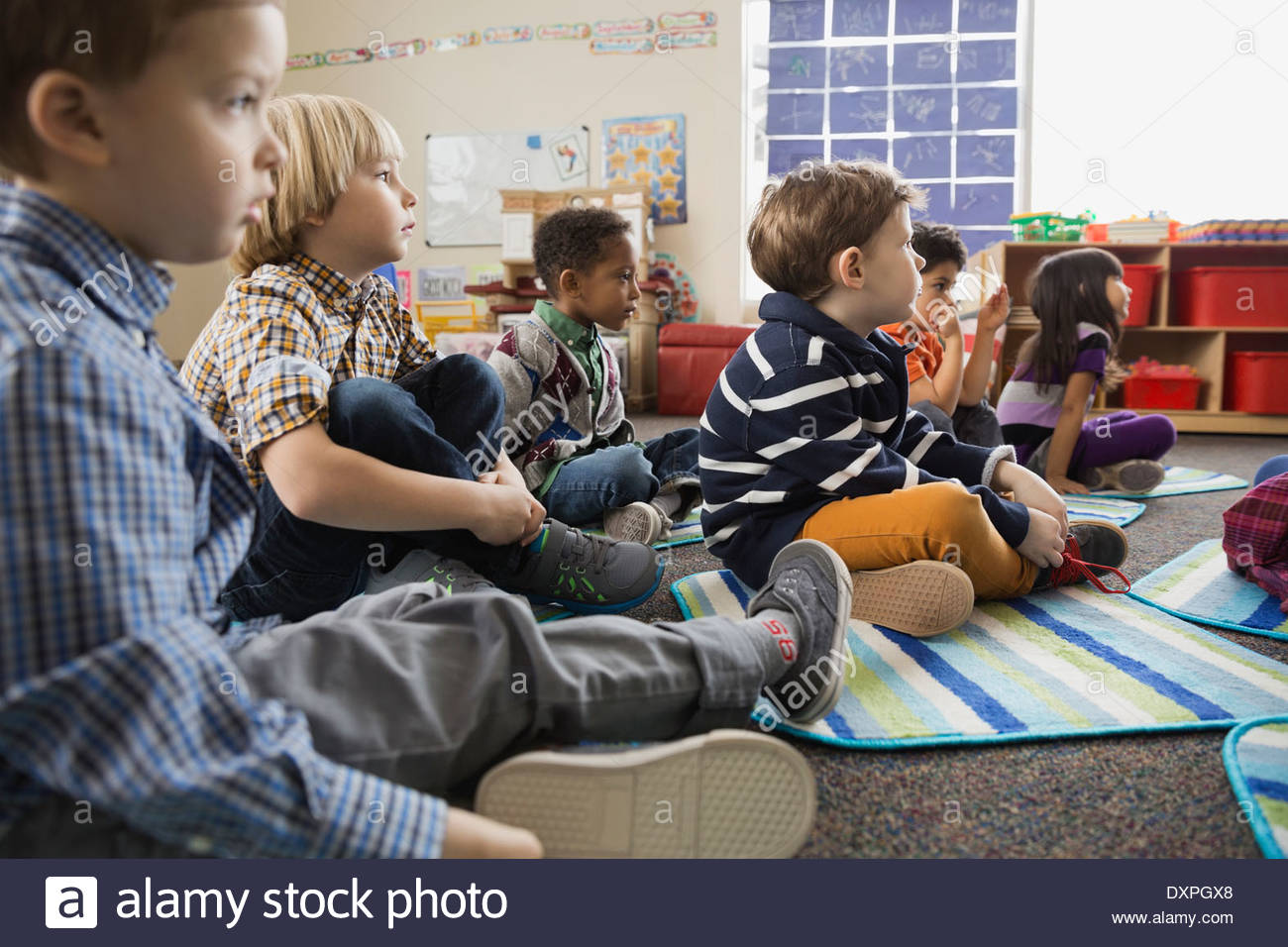 Niños sentados en el suelo en la escuela elemental Foto de stock