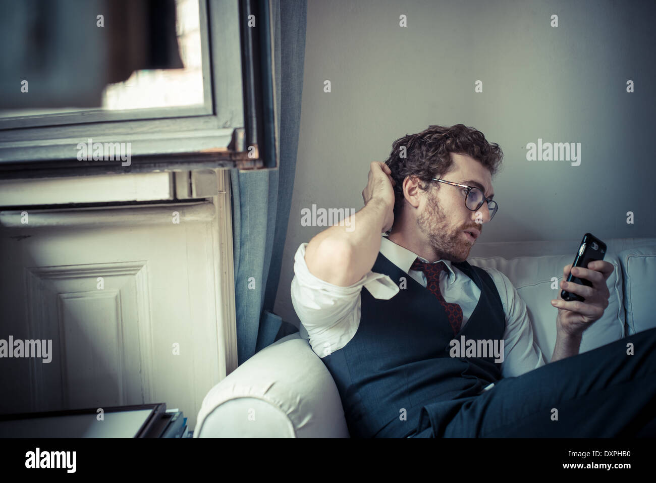 Elegante moda atractiva hipster hombre sobre el teléfono en casa Foto de stock