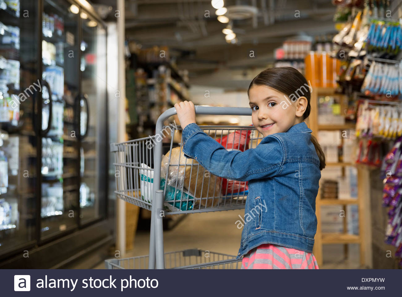 Retrato de niña empujando a compras en el mercado Foto de stock
