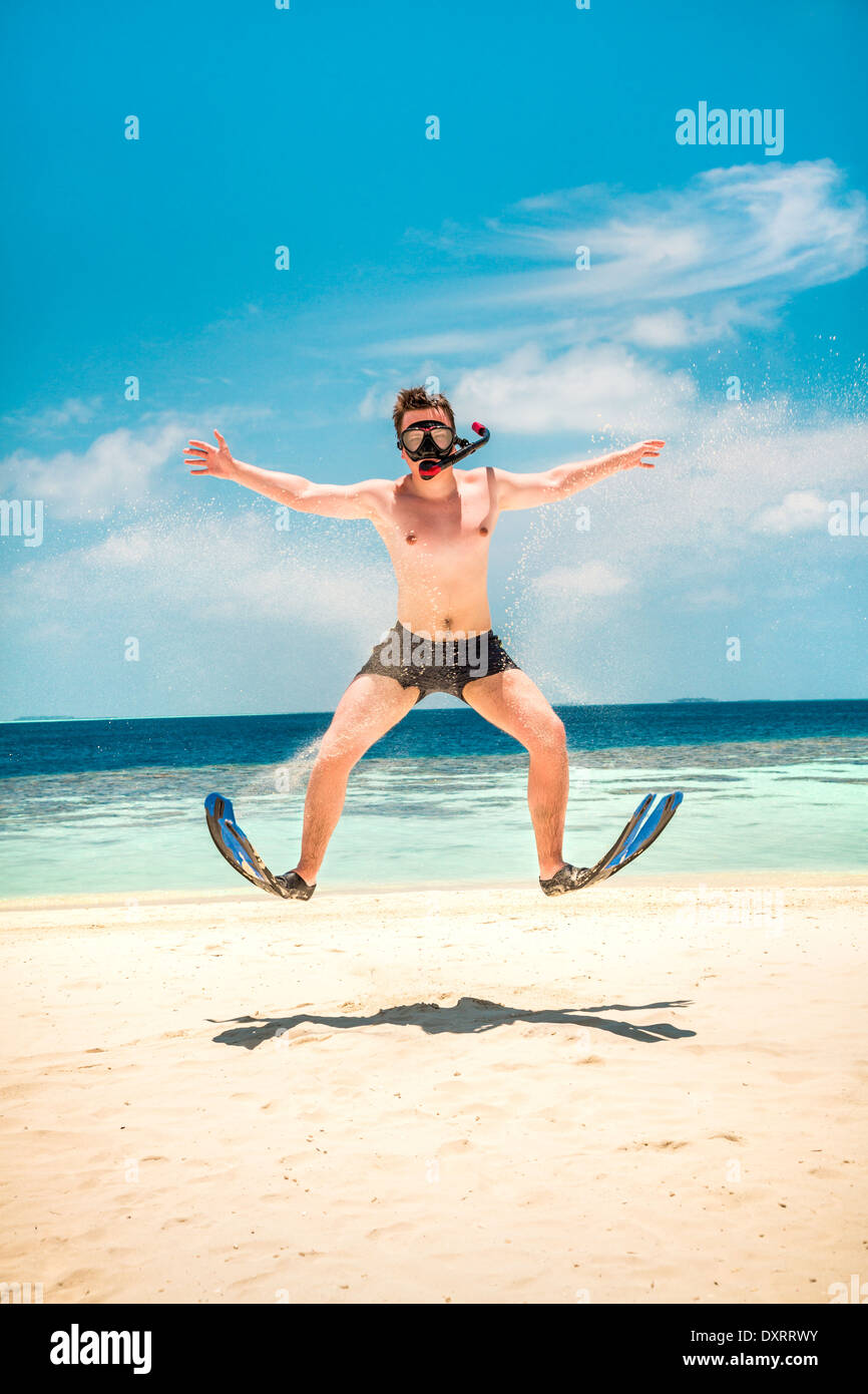Gracioso hombre saltando en aletas y máscara. Para vacaciones en una playa tropical en Islas Maldivas. Foto de stock