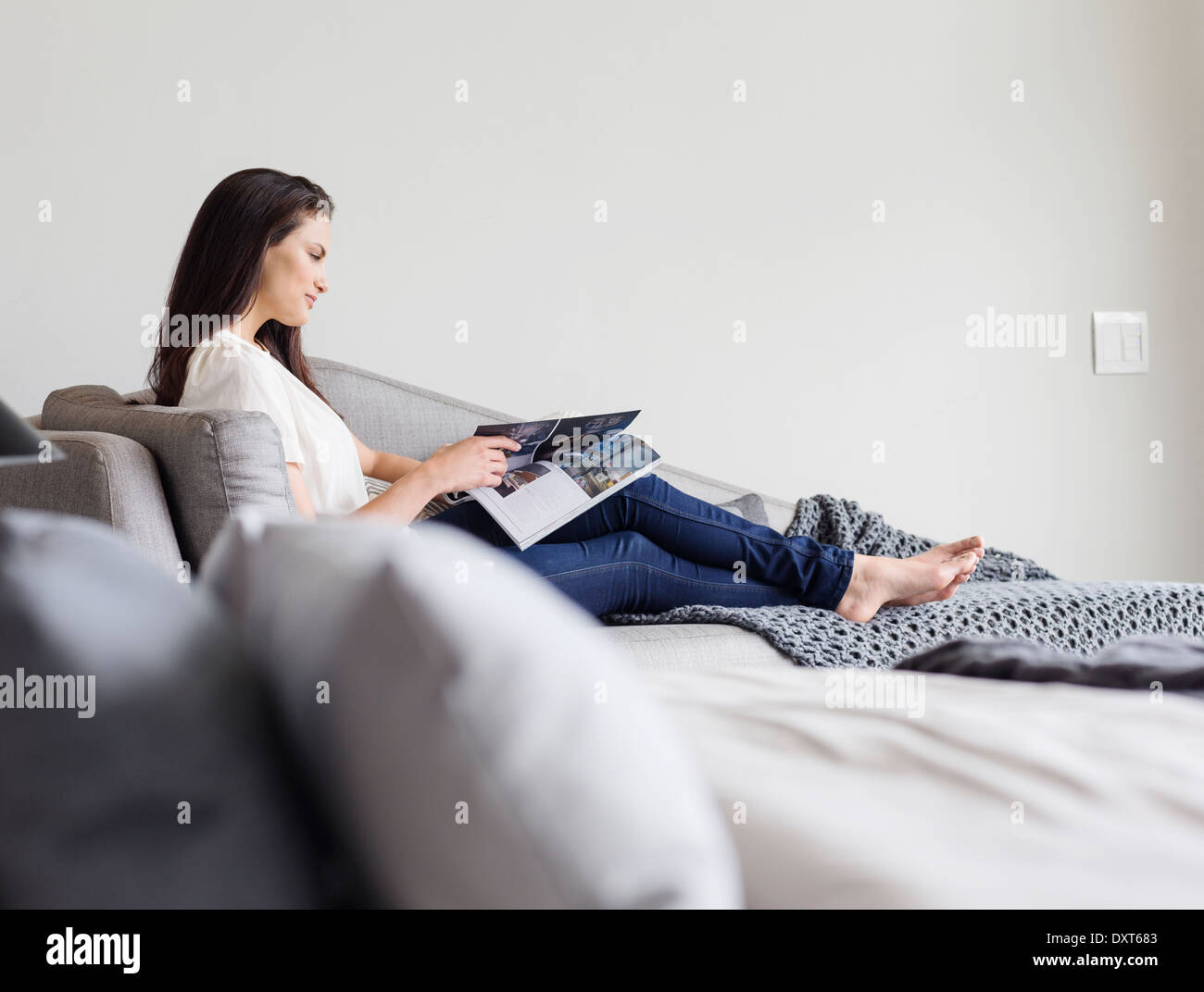 Mujer leyendo revista sobre chaise lounge Foto de stock