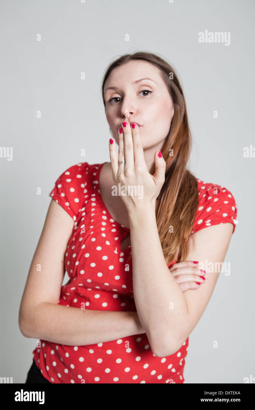 Retrato de estudio de atractiva mujer vistiendo una blusa roja irregular  con guiaba labios soplando un beso Fotografía de stock - Alamy