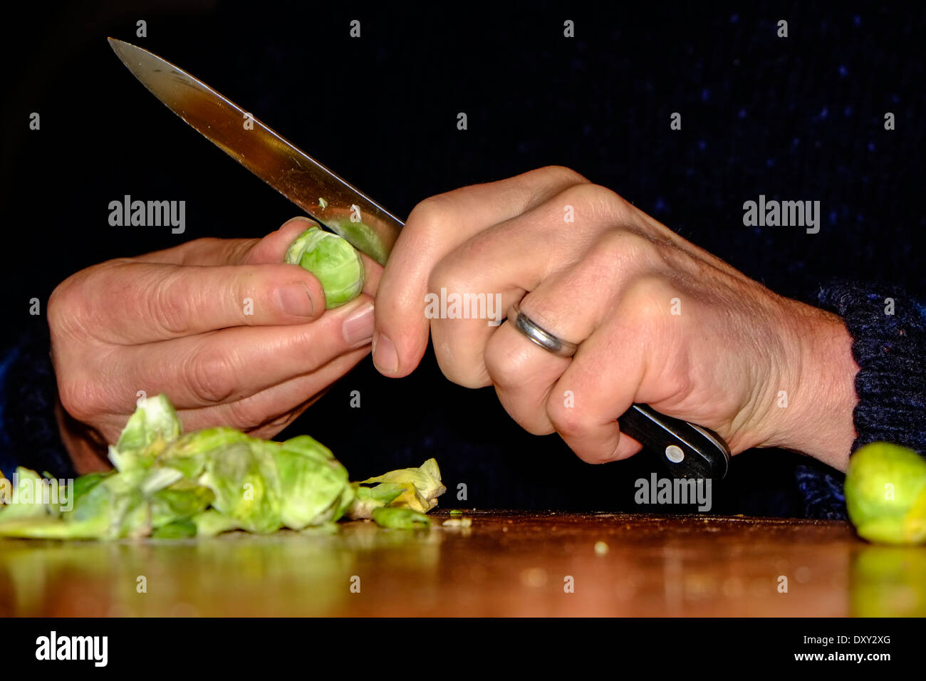 Primer plano de manos pelando brotes orgánicos frescos de bruselas Foto de stock