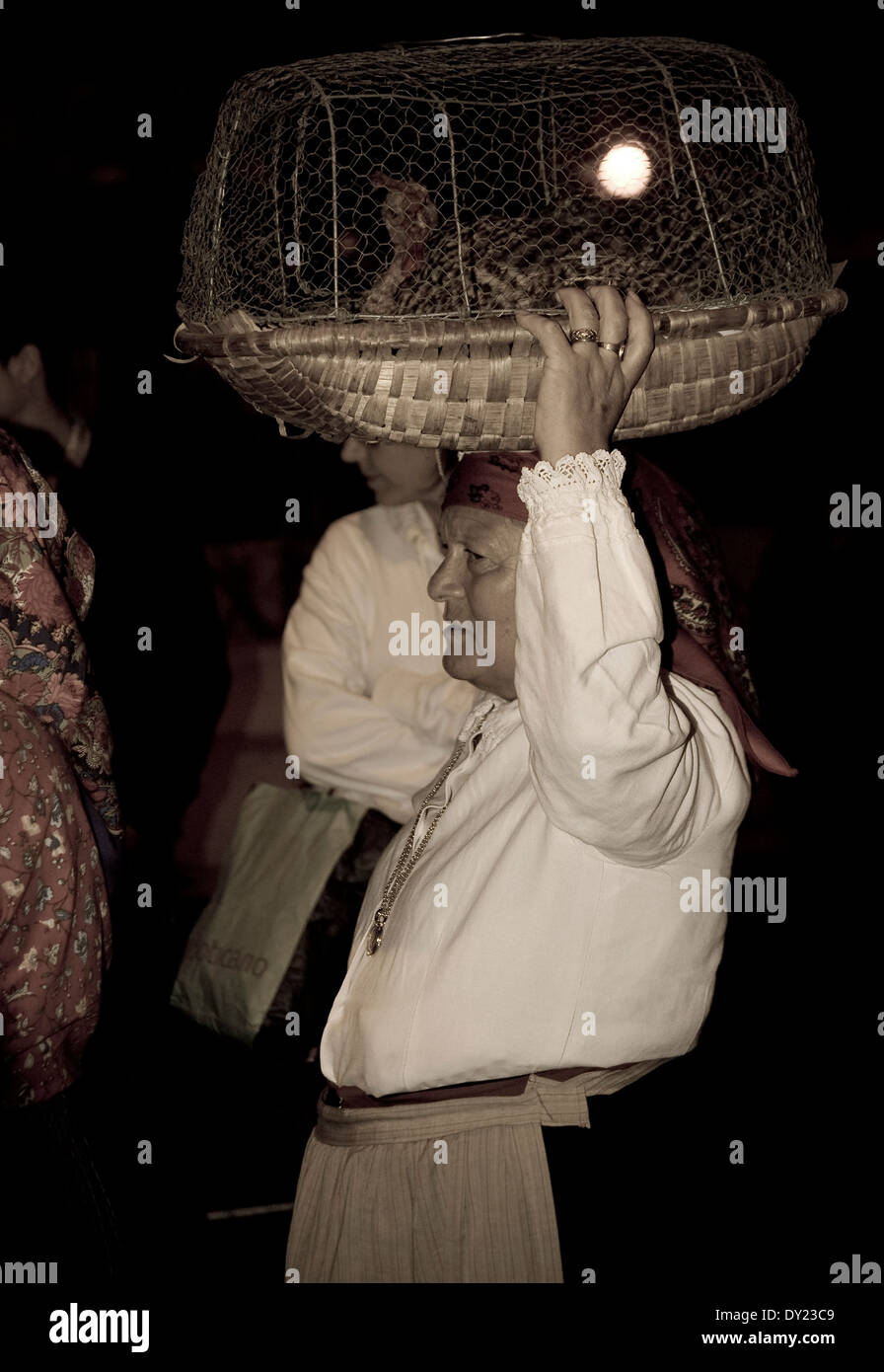 Una anciana llevando una jaula con una gallina en la cabeza, en el tradicional desfile de Oporto Foto de stock