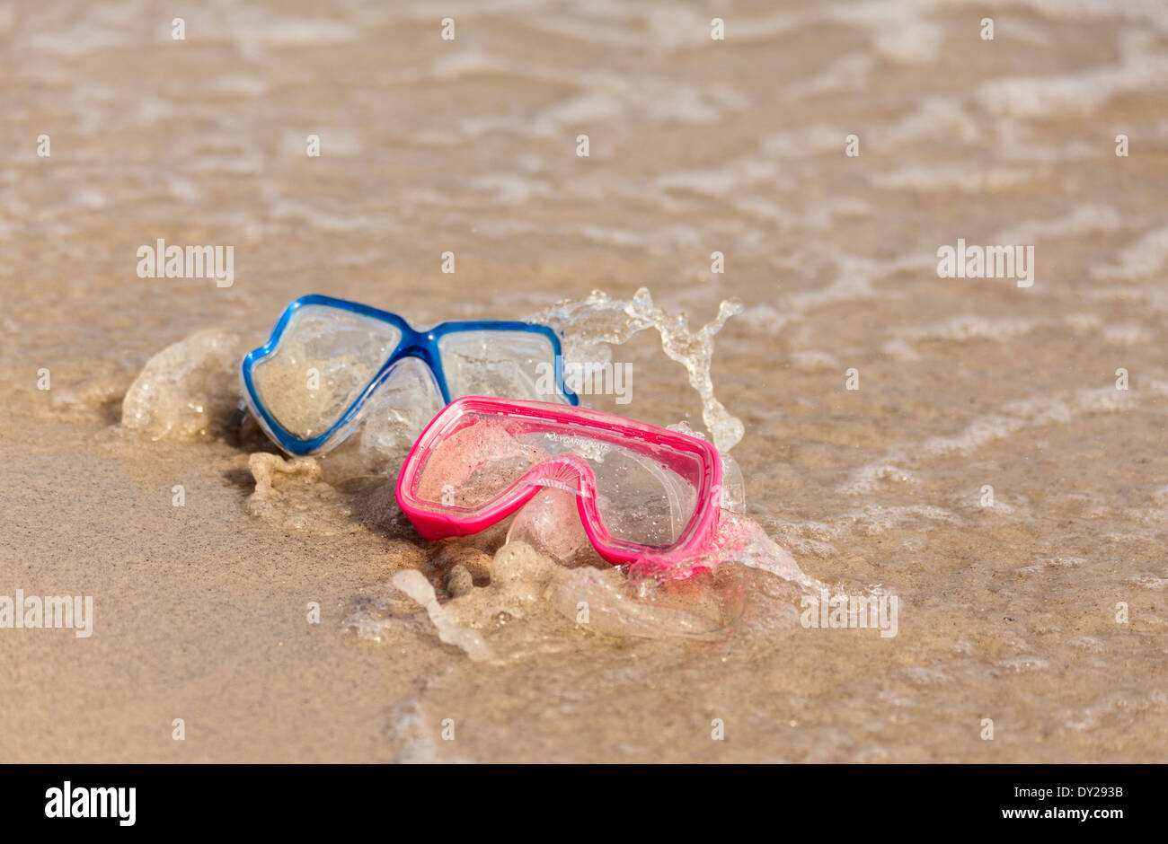 Divertida actividad de agua. dos máscaras de buceo en la playa salpicada por las olas Foto de stock