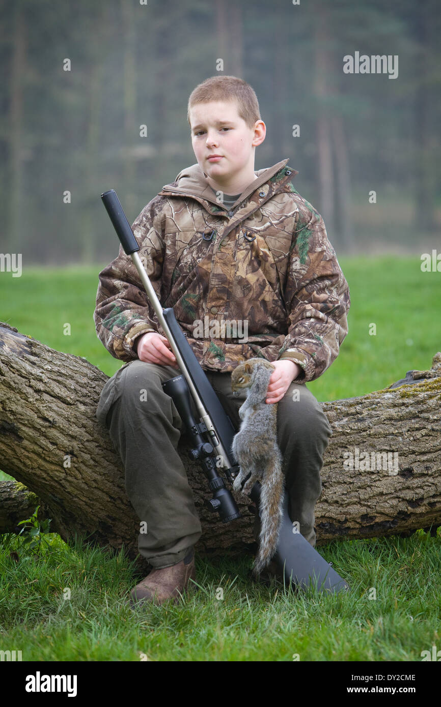 Un hombre joven con un fusil, disparar las plagas durante el día en el campo Foto de stock