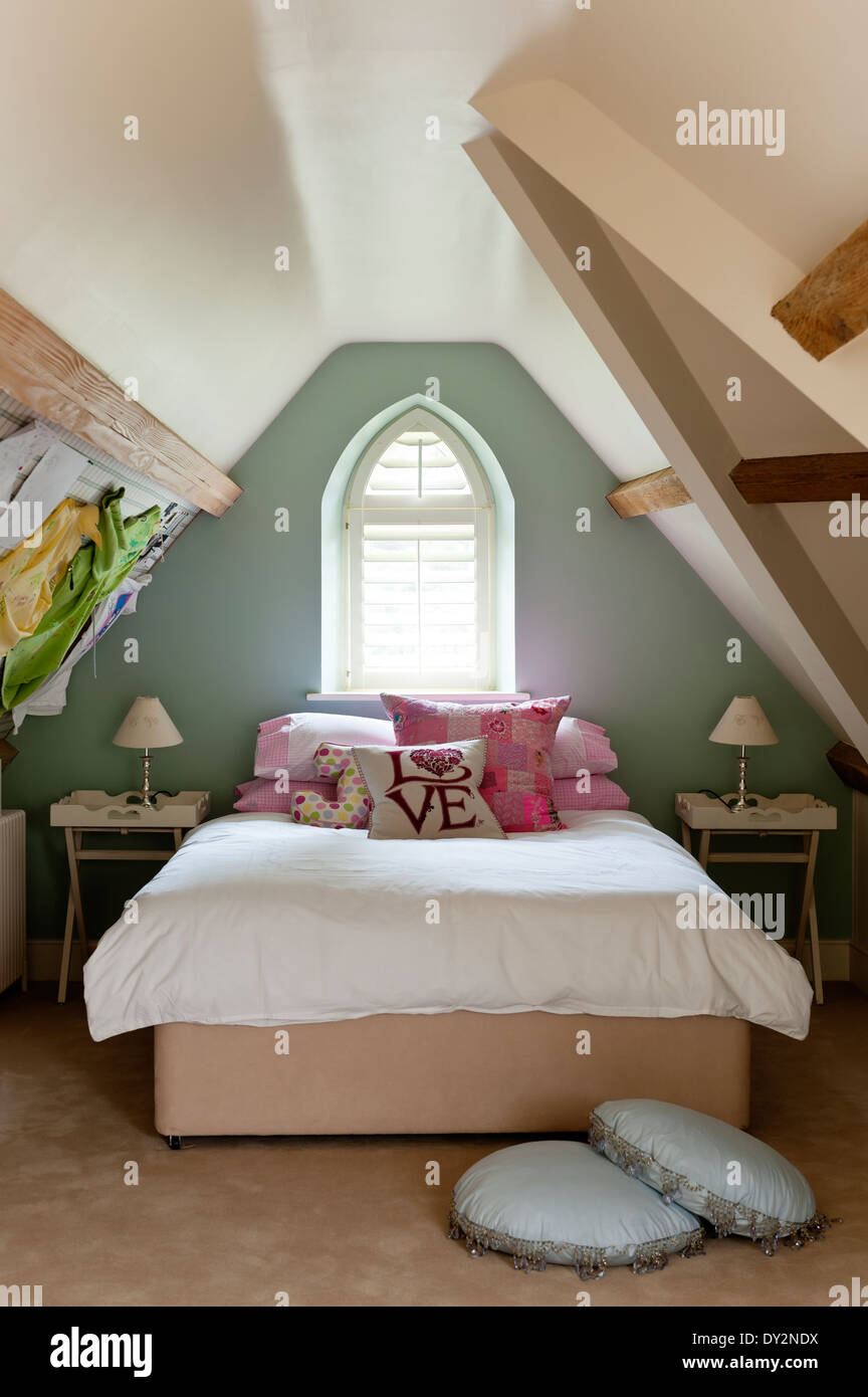 Las niñas habitación abuhardillada con muros inclinados y ventana arqueada Foto de stock