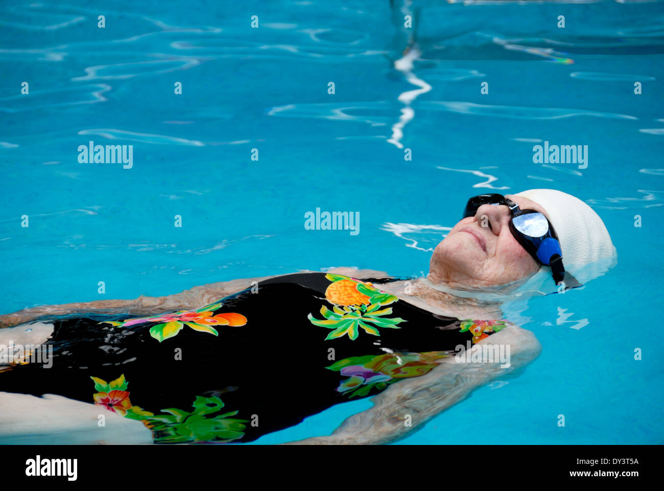 Una mujer senior citizen en traje de baño, gorra y gafas natación