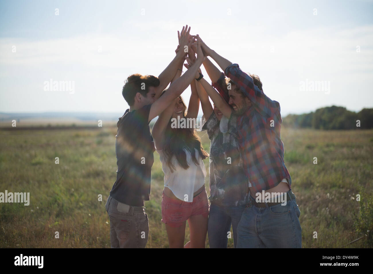Cuatro amigos cogidos de la mano con los brazos levantados Foto de stock