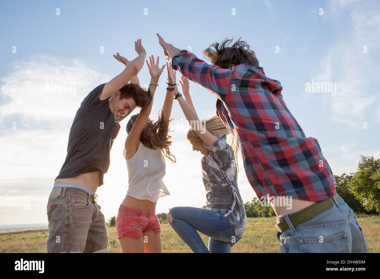 Cuatro amigos saltando con los brazos levantados Foto de stock