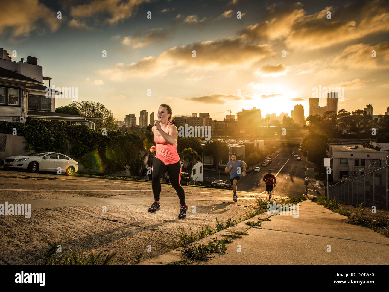 Equipo de corredores subiendo una empinada colina de la ciudad Foto de stock