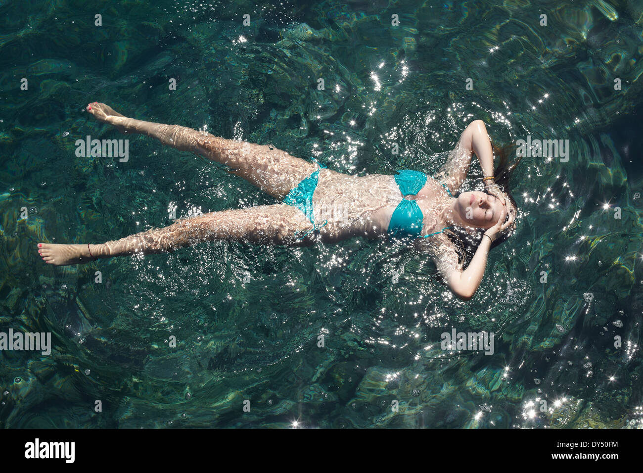 Adolescente flotando con los ojos cerrados en el mar Foto de stock