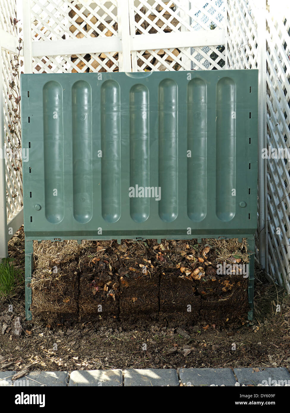 Cubo de compostaje de plástico verde con parte inferior retirado para mostrar avanzado proceso de descomposición del suelo Foto de stock