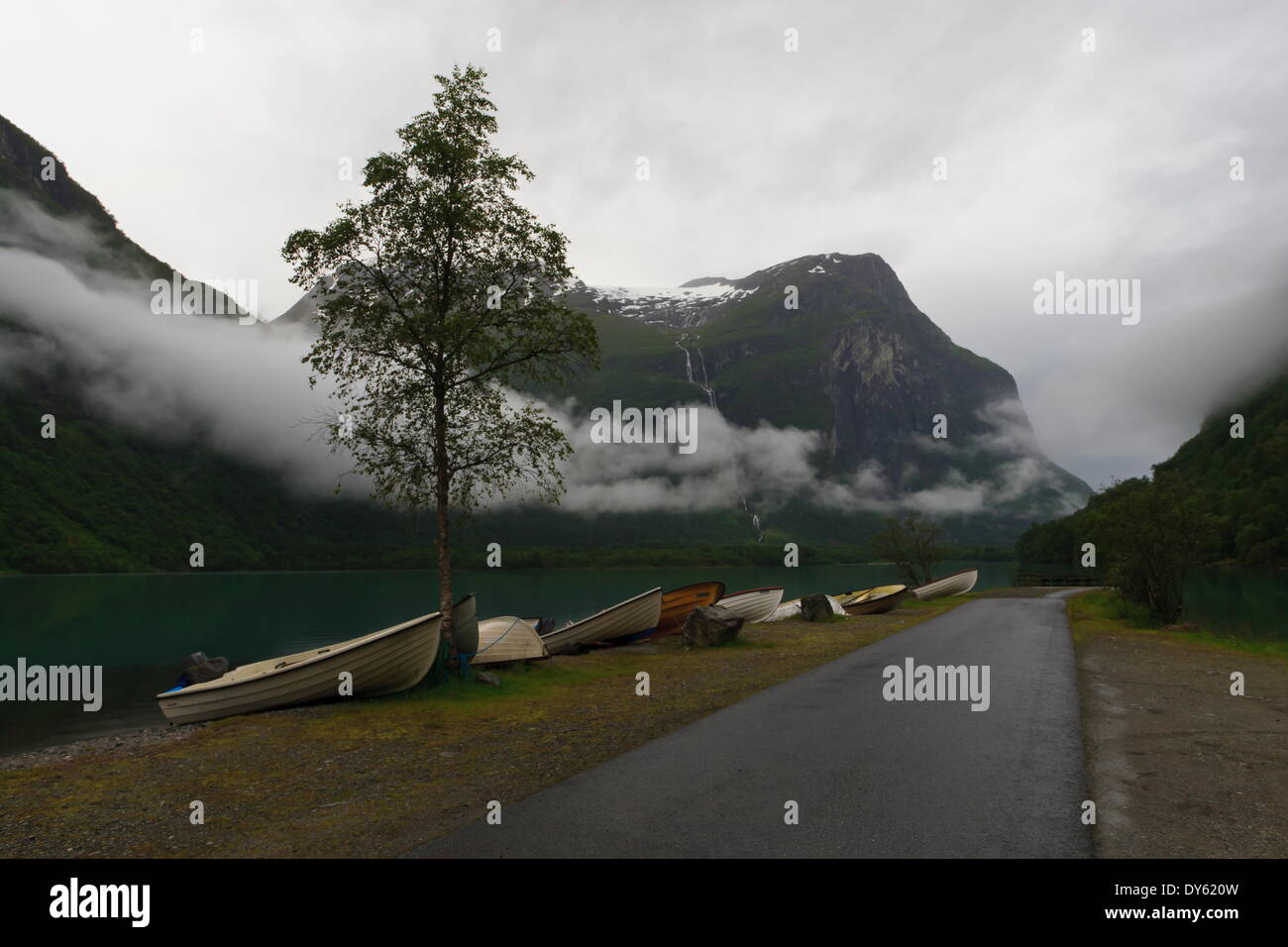 Botes a remo, el lago, las montañas y las nubes bajas, el lago Lovatnet, Noruega, Escandinavia, Europa Foto de stock