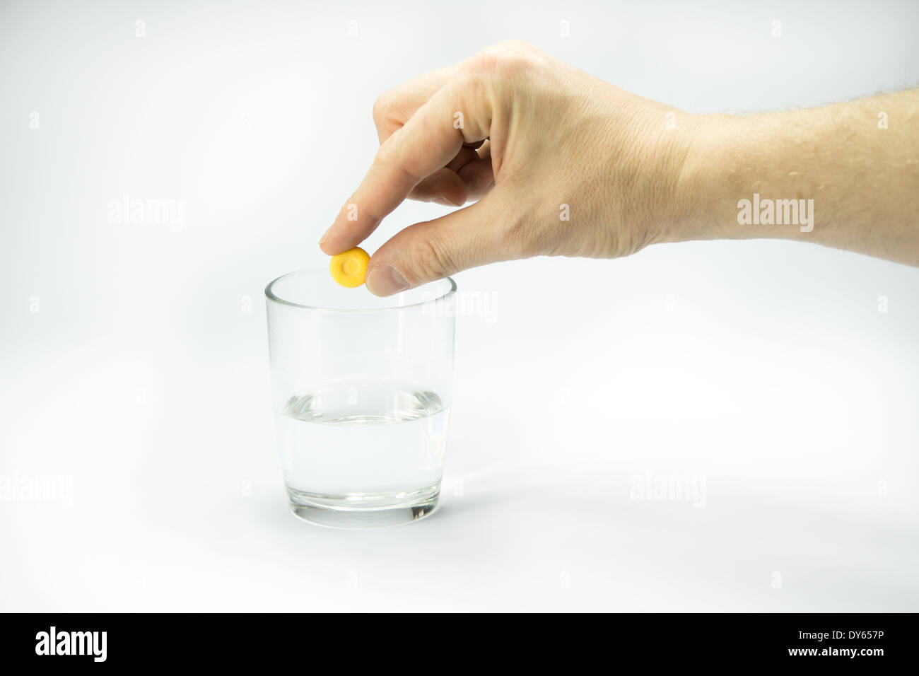 Poner mano a una tableta en un vaso de agua Foto de stock