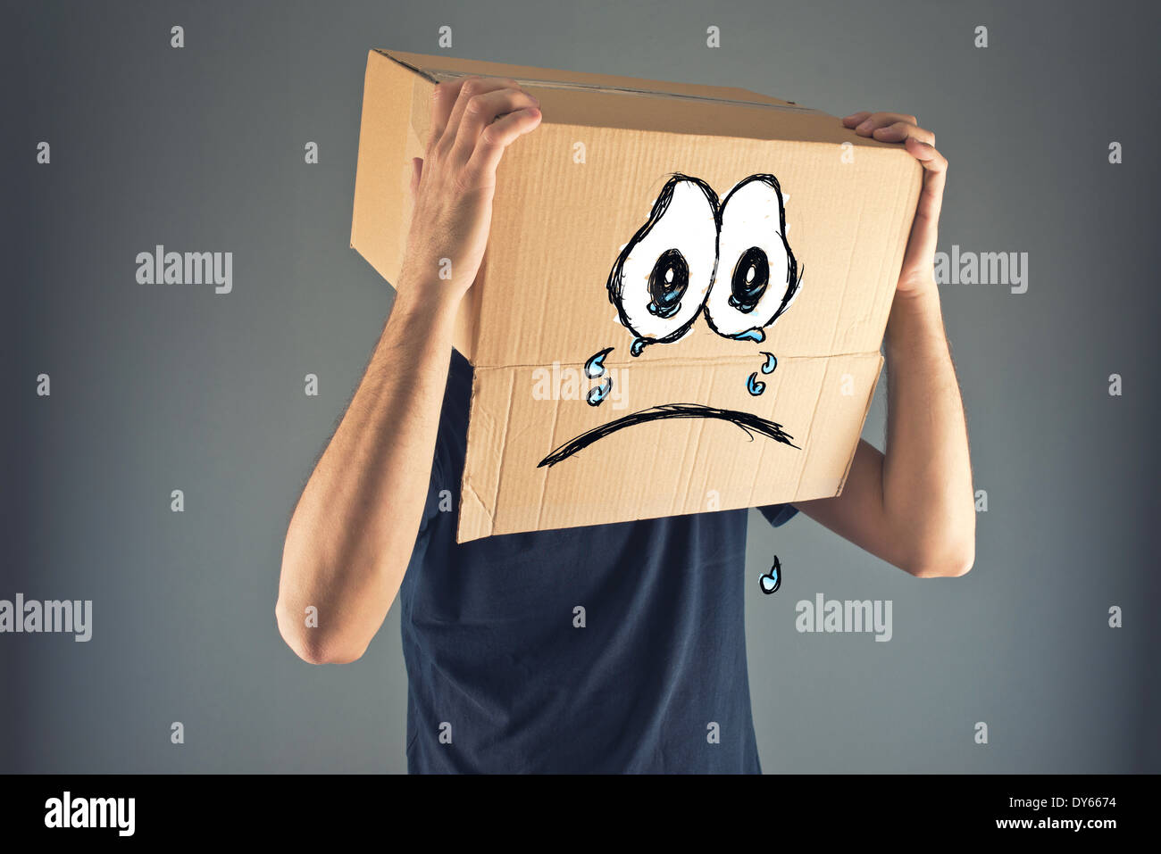 Hombre con caja de cartón en su cabeza y su Cara llorosa Triste expresión. Concepto de tristeza y depresión. Foto de stock