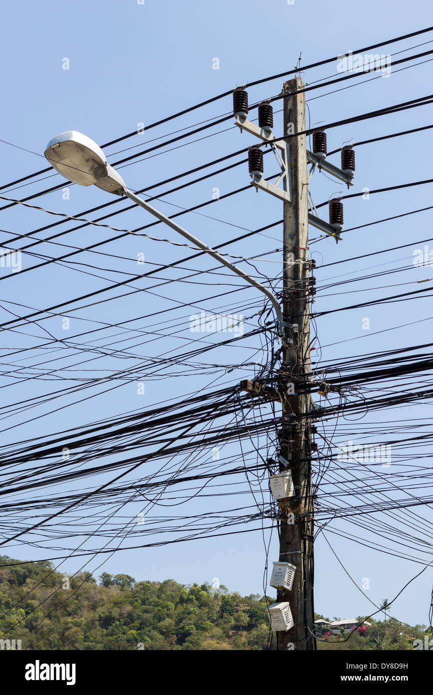 Primer plano de un caos de cables y una lámpara en un polo de alimentación Foto de stock