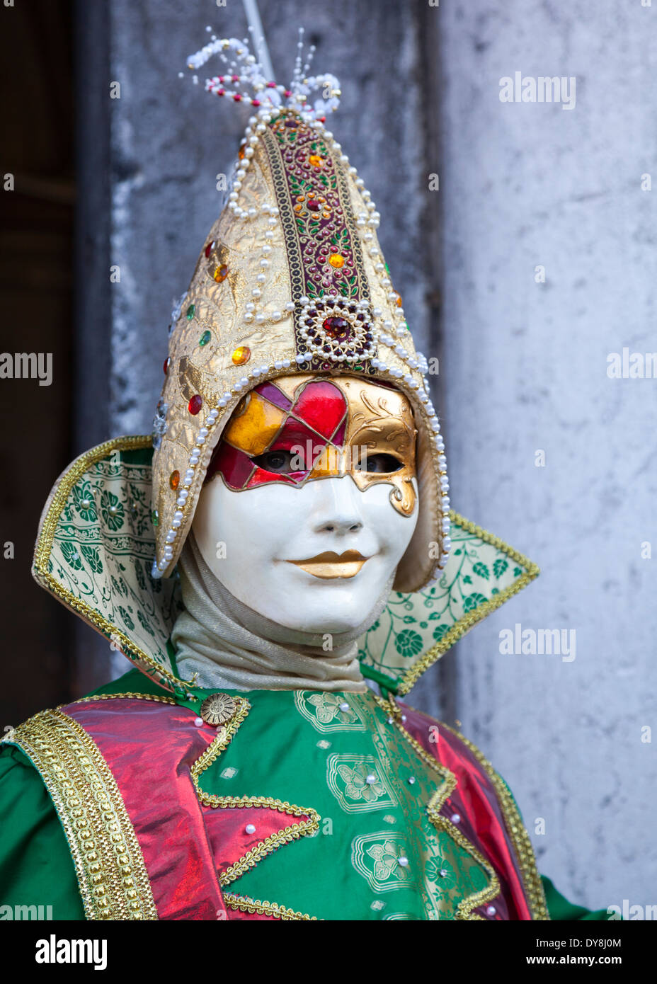 Cerca de bufón enmascarado en traje brillante durante el carnaval de Venecia Foto de stock