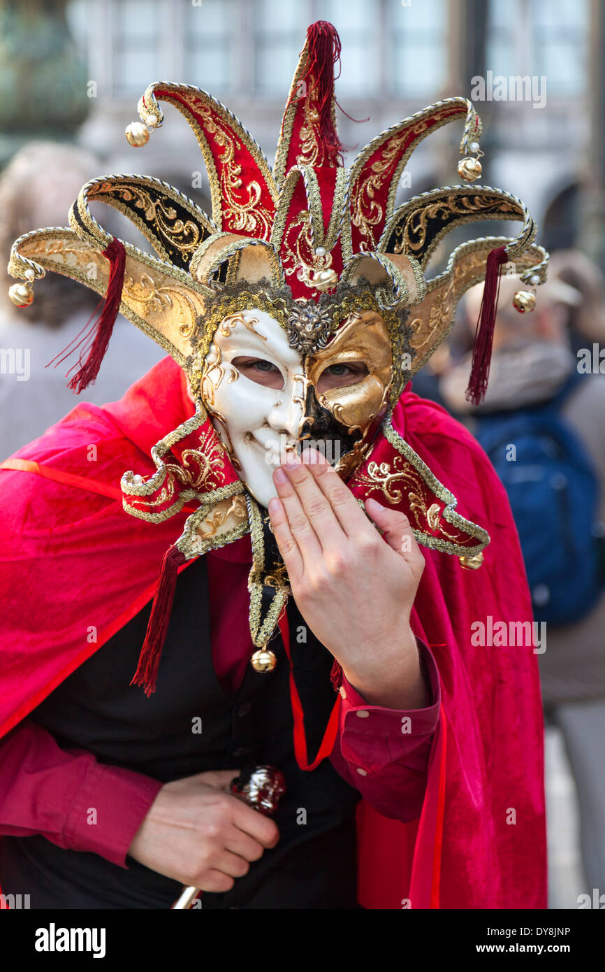 Disfrazada Arlecchino Harlequin o bufón con máscara sonríe a cámara durante el carnaval de Venecia, Carnevale di Venezia, Italia Foto de stock