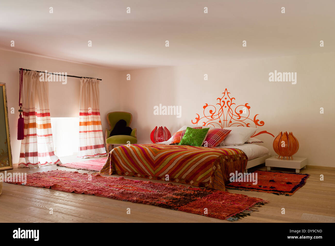 Indios y cálida inspiración marroquí dormitorio con telas de colores brillantes y suelos de roble lima Foto de stock