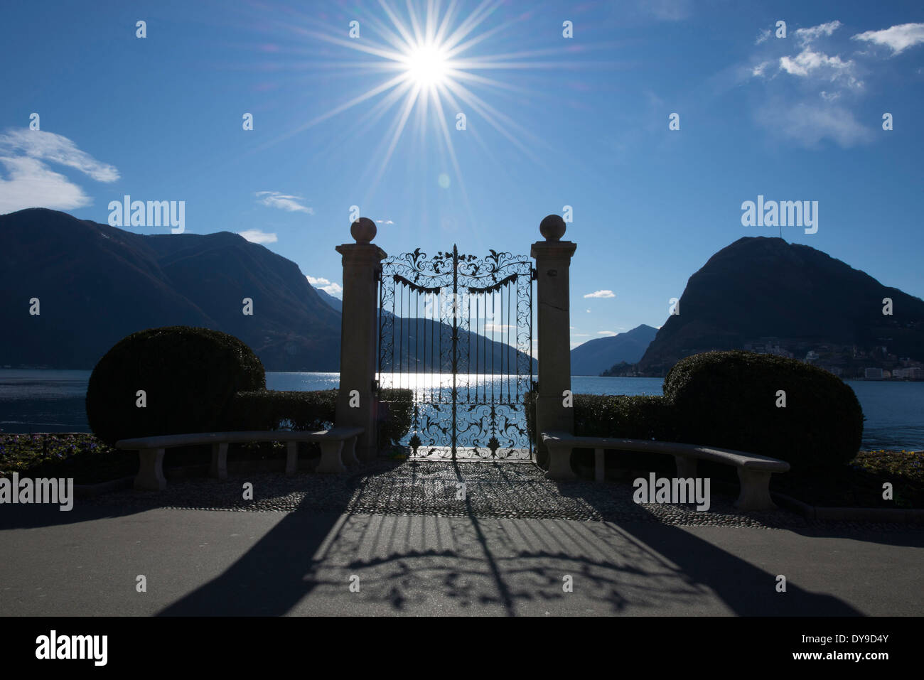 La compuerta de un lago alpino en retroiluminados con sunbeam y montaña en Lugano Suiza Ticino, Europa Foto de stock
