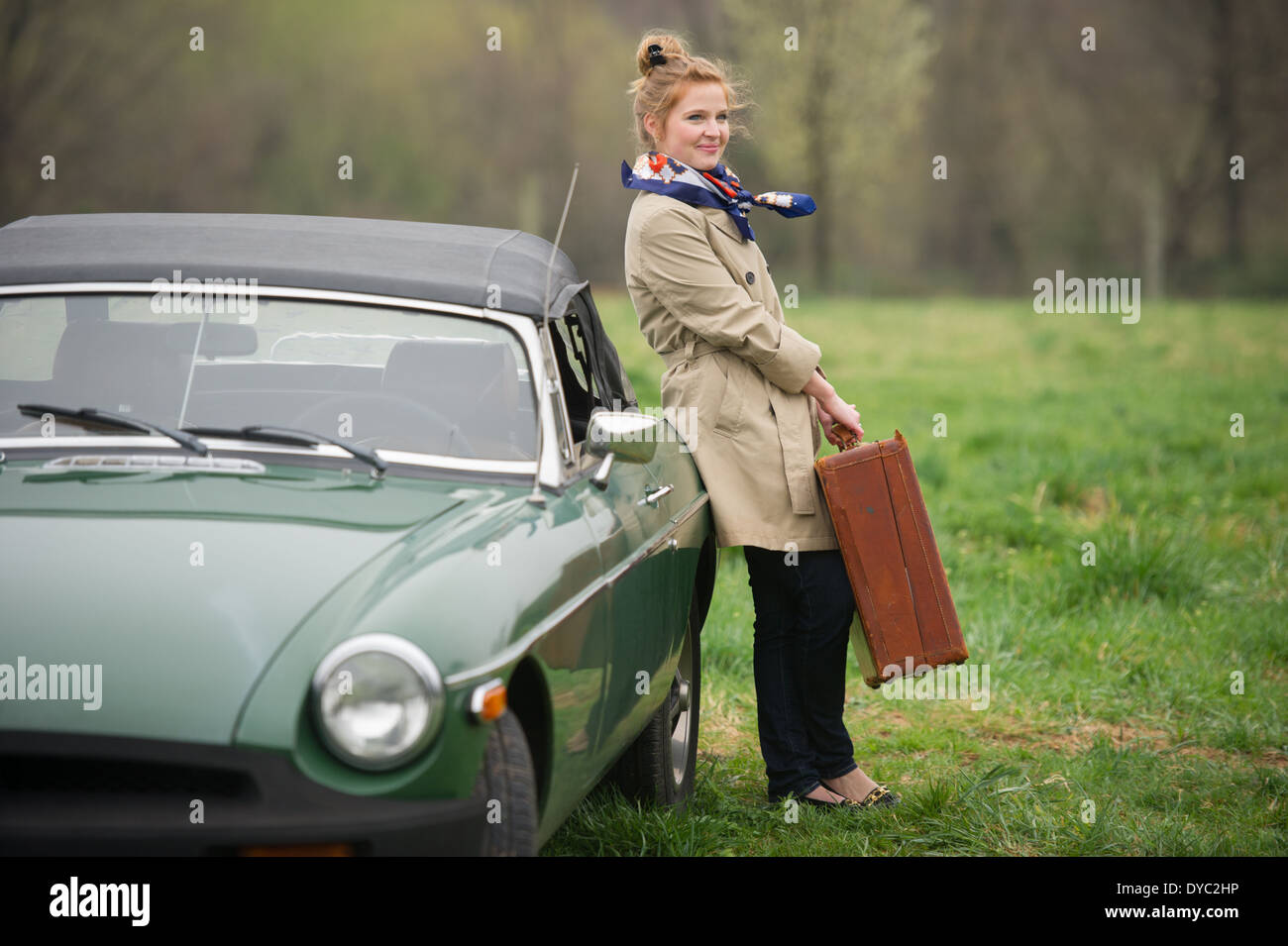 Mujer con empaquetados en bolsas de viaje junto al clásico coche deportivo británico Foto de stock