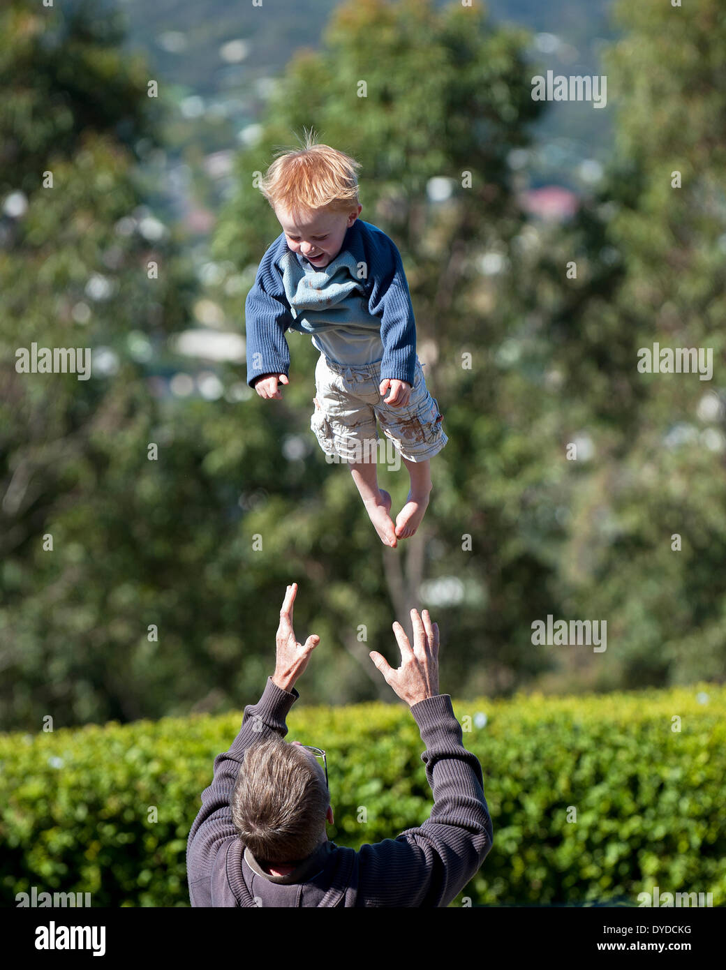 Un padre lanzando su joven hijo en el aire. Foto de stock