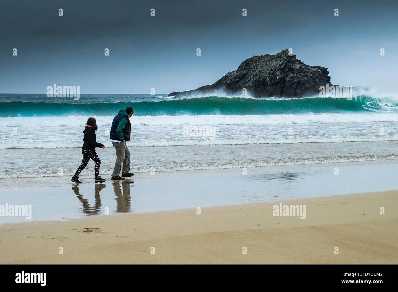 Un padre y su hija caminando por la playa Crantock en malas condiciones climáticas. Foto de stock