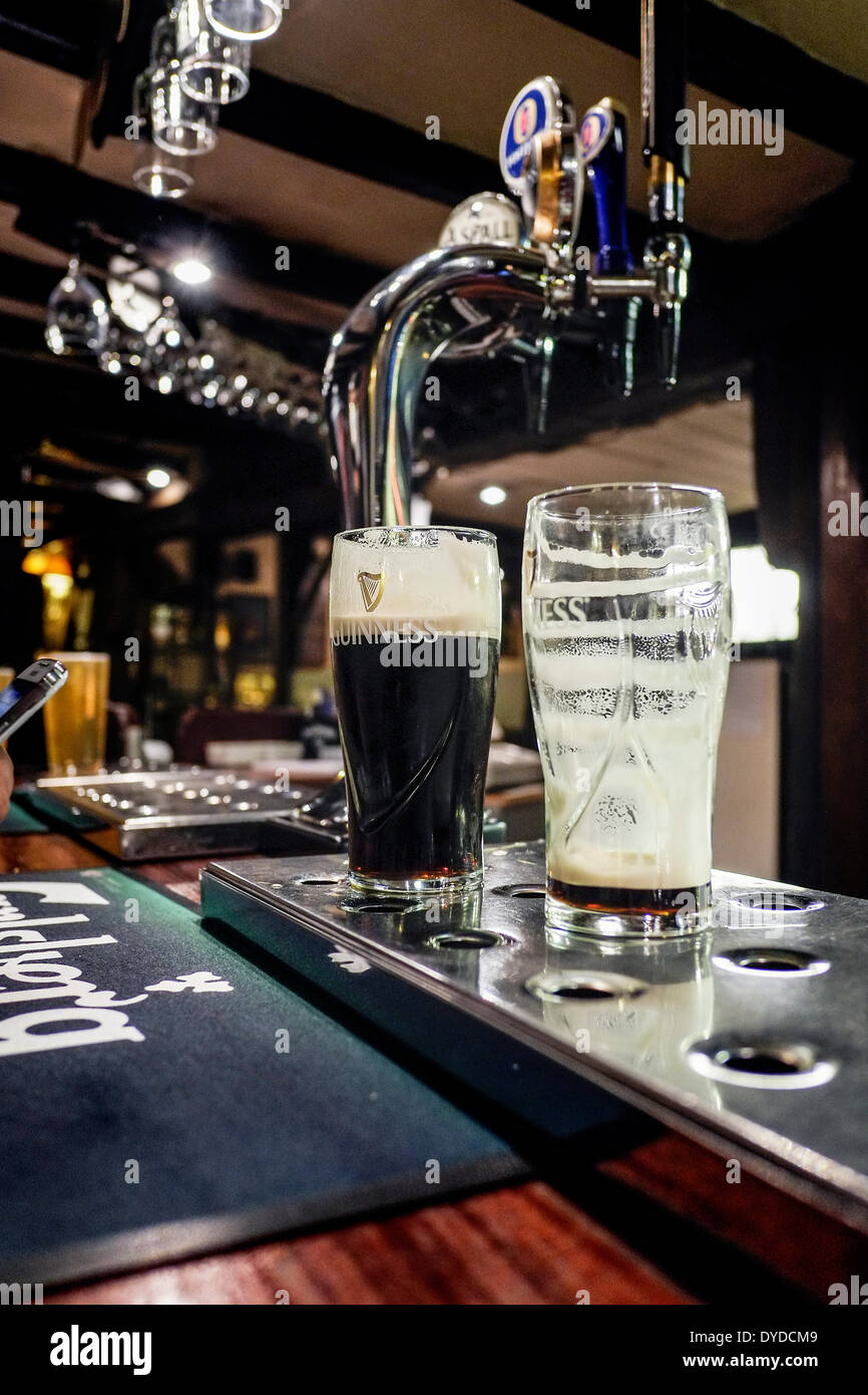 Pinta vasos de Guinness en la barra de un bar. Foto de stock