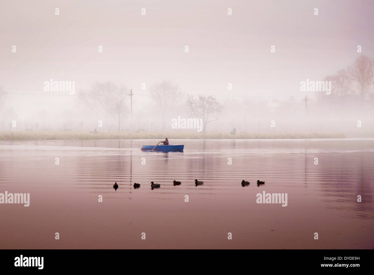 Los hombres en botes por el río de viaje en la niebla por la calurosa mañana de otoño Foto de stock