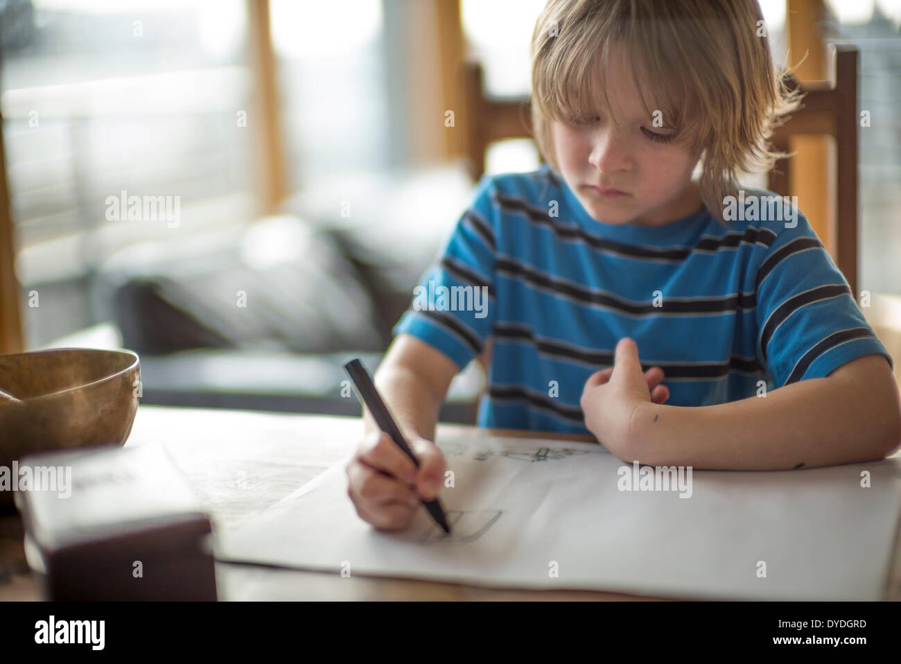 Niño de siete años en la mesa de dibujo. Foto de stock