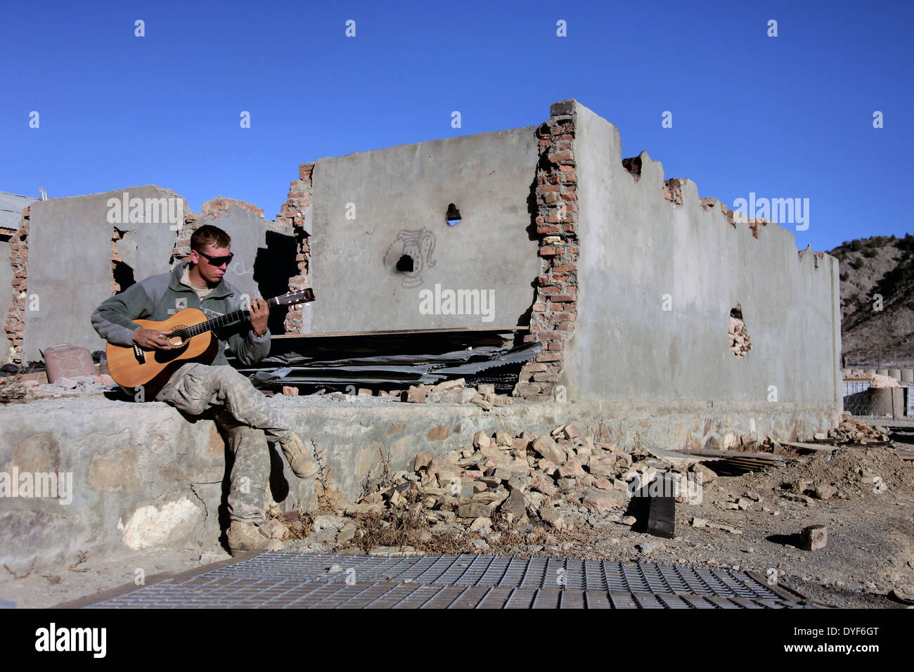 El sargento del ejército estadounidense. Michael Simmons juega su guitarra acústica durante algún tiempo en el combate Outpost Muñoz Noviembre 12, 2009 en Afganistán. Foto de stock