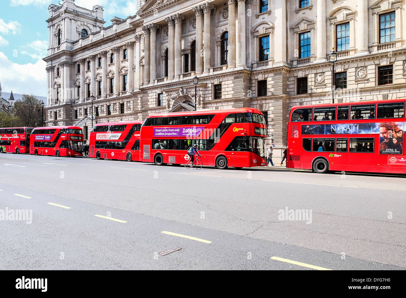 Cinco icónicos autobuses rojos de Londres haciendo cola en una parada de autobús. Foto de stock