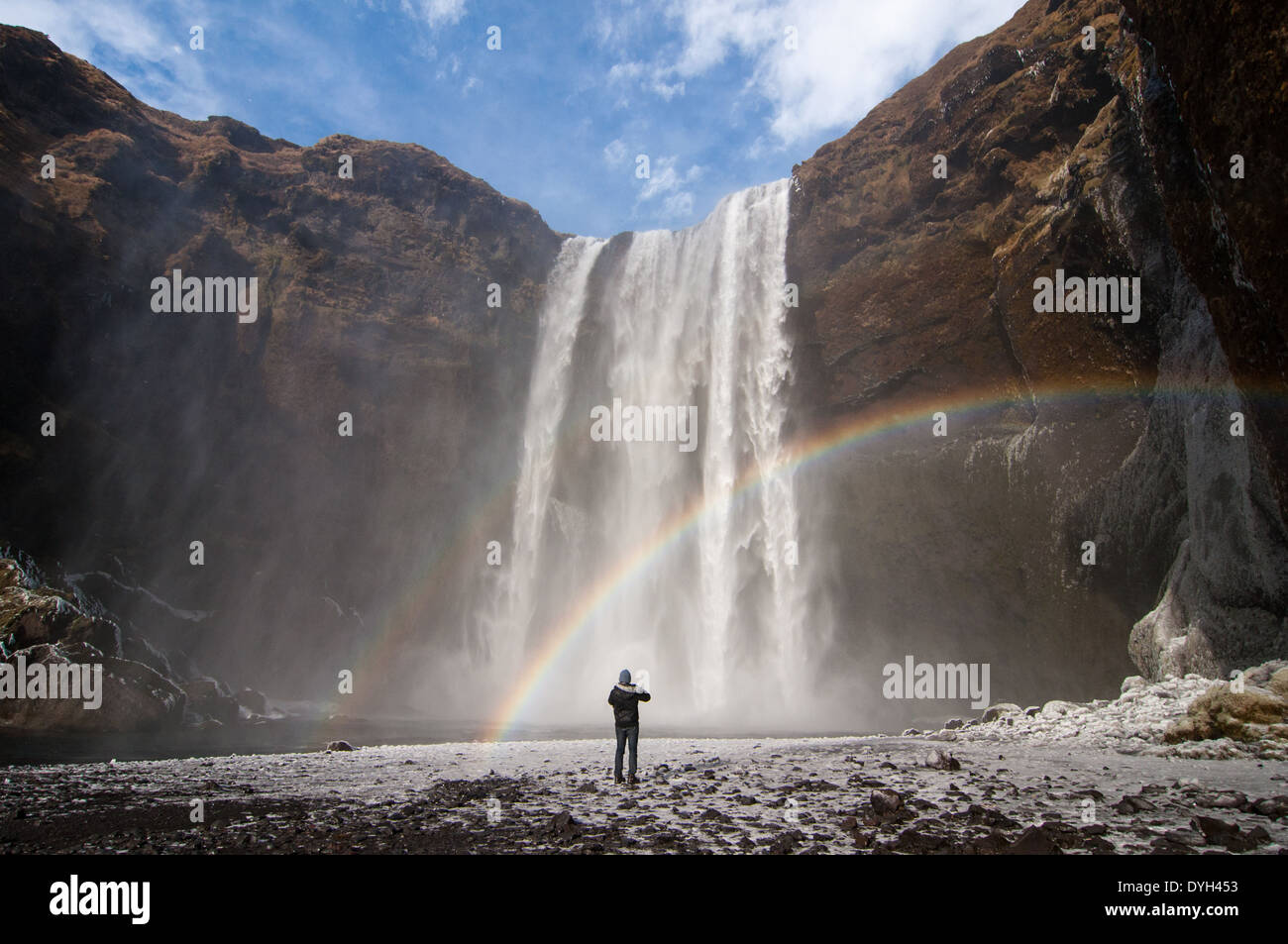 Un viajero ventures cerca de Skogafoss, en el sur de Islandia, para una mejor vista de la olla de oro al final del arco iris. Foto de stock