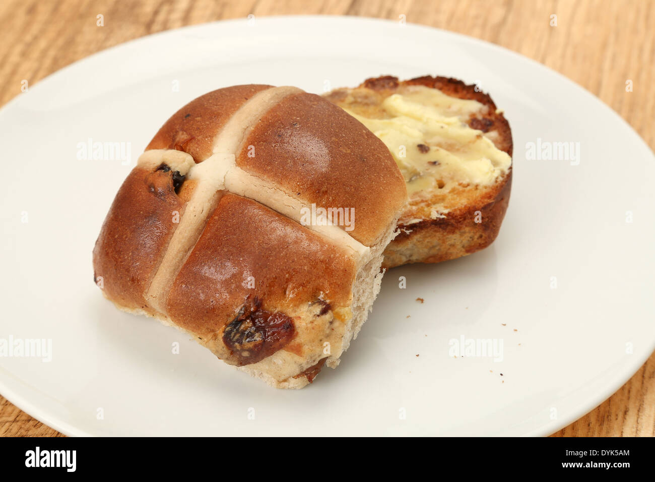 Hot Cross bun cortar por la mitad y con mantequilla Foto de stock