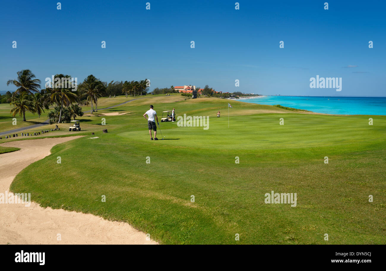 Los golfistas jugando el green del hoyo 18 del club de golf de Varadero cuba con mar caribe Foto de stock
