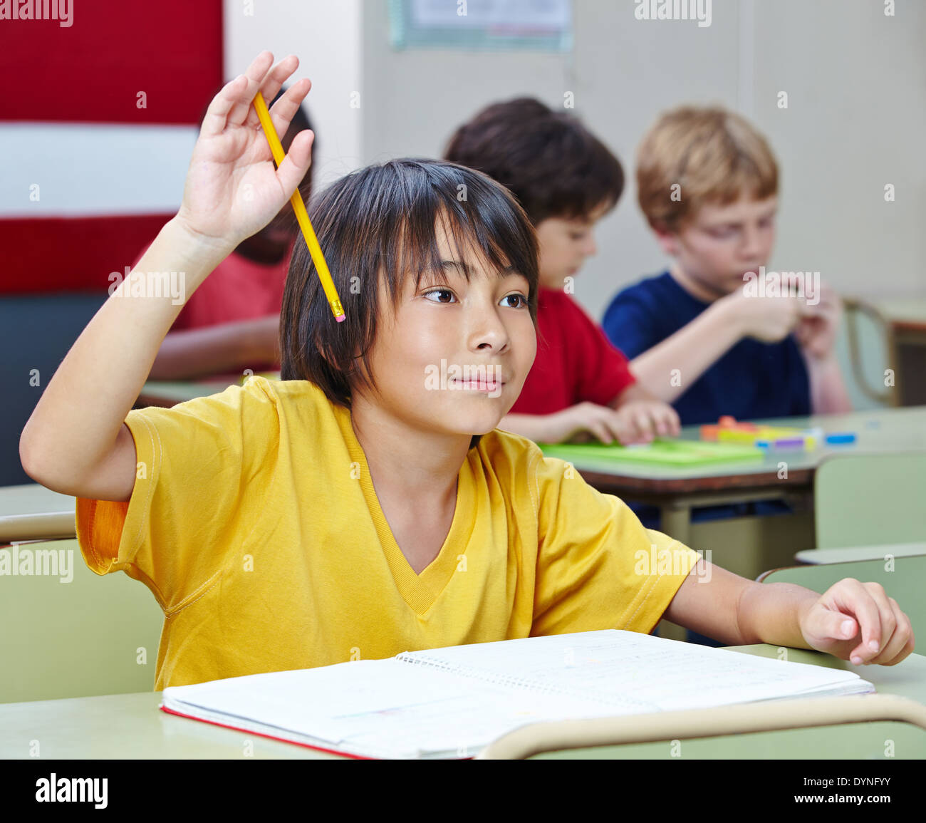 Estudiante de la escuela elemental japonesa levantando su mano en clase Foto de stock