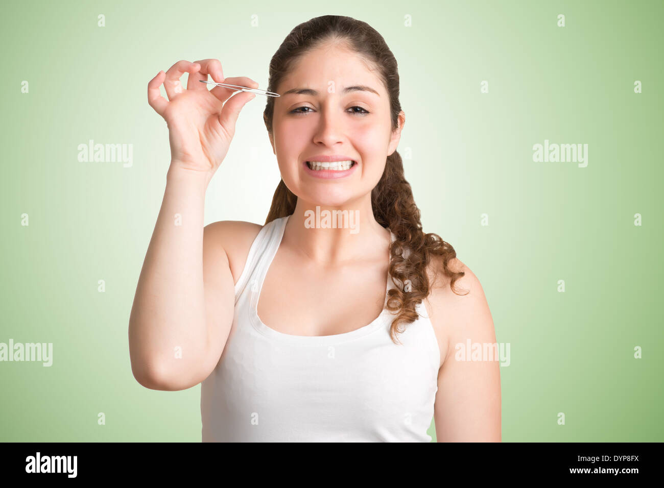 Mujer depilarse las cejas con un painfull su mirada en su rostro, aislado Foto de stock