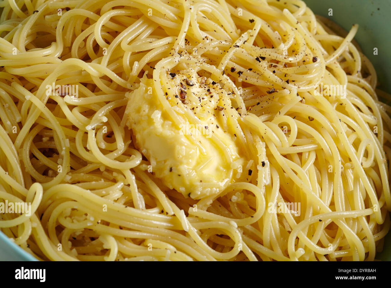 Mantequilla derritiendo sobre espaguetis con pimienta y queso parmesano. Foto de stock