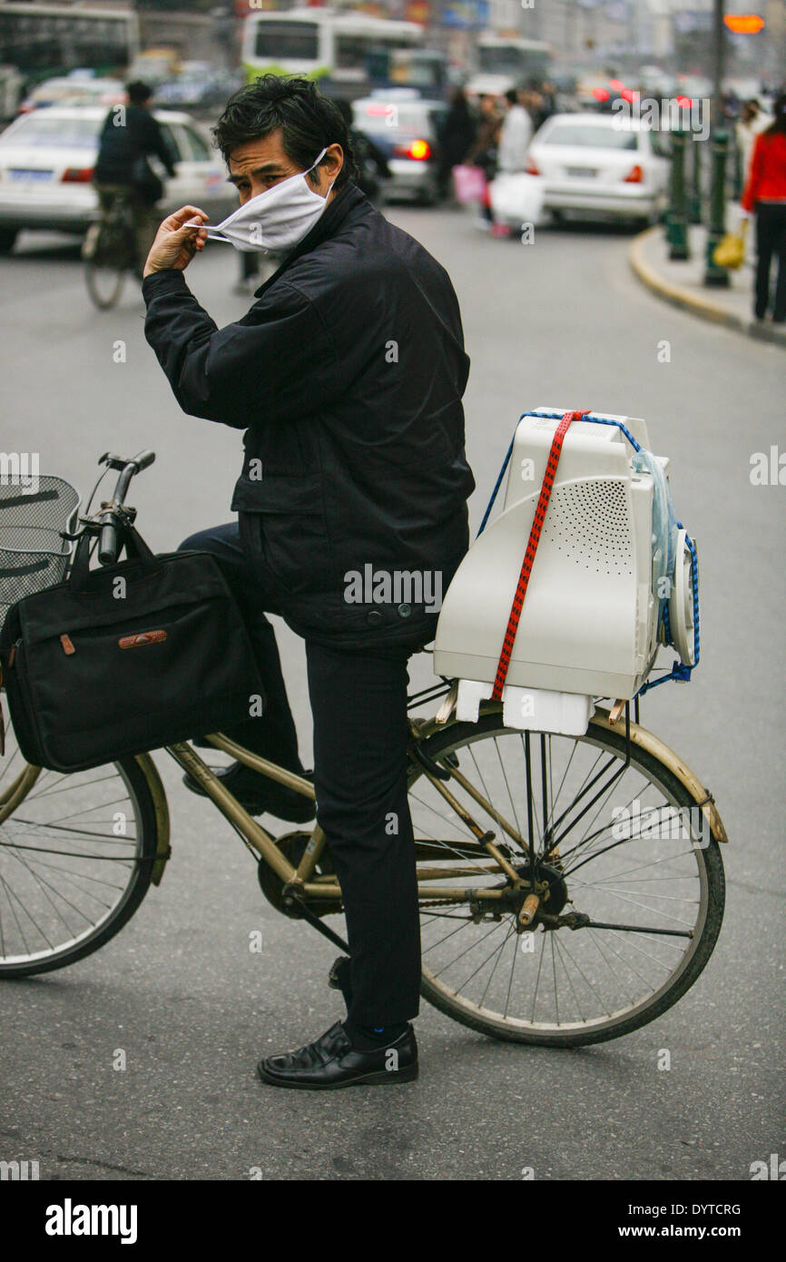 Un ciclista ajustar su máscara en una carretera Foto de stock