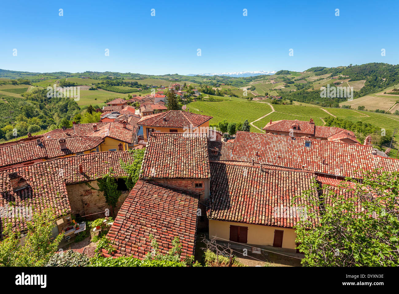 Techos de teja roja en pequeño pueblo y colinas verdes bajo un cielo azul  en la primavera en el Piamonte, Norte de Italia Fotografía de stock - Alamy
