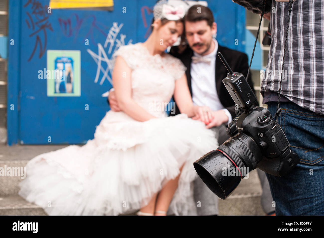 Fotógrafo de bodas alternativos en un tiroteo con una pareja en Vintage ropas mirando el anillo de bodas en frente de graffiti Foto de stock