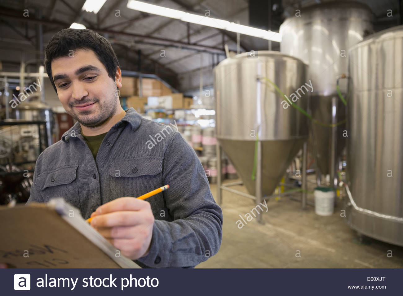 Trabajador de cervecería con portapapeles cerca de cubas Foto de stock