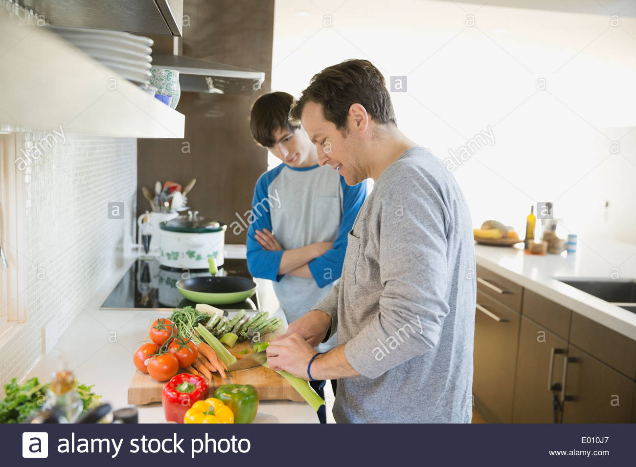 Hijo de padre enseñando a cocinar en la cocina Foto de stock