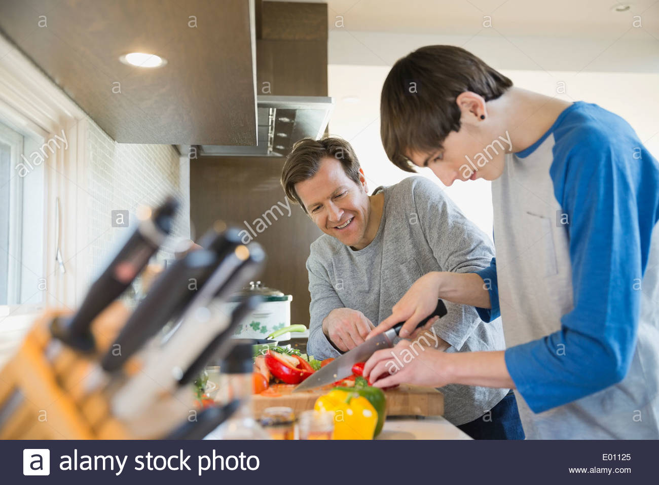 Hijo de padre enseñando a cocinar en la cocina Foto de stock